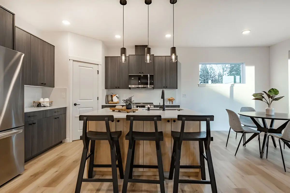 Modern kitchen with dark cabinets, wood island, black barstools, and pendant lighting