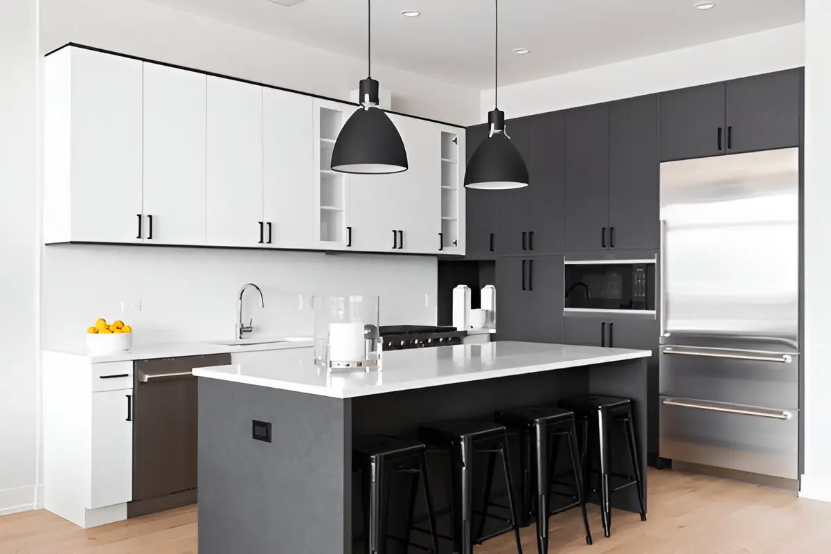 Minimalist black and white kitchen with a large island, pendant lighting, stainless steel appliances, and high-contrast cabinetry